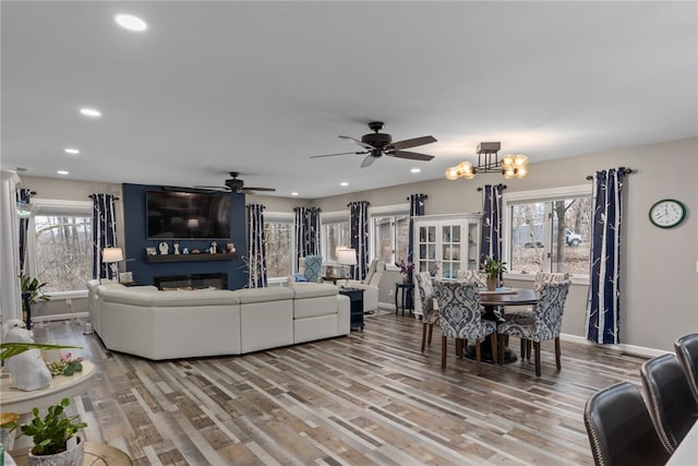 living room featuring light hardwood / wood-style flooring, a large fireplace, and ceiling fan