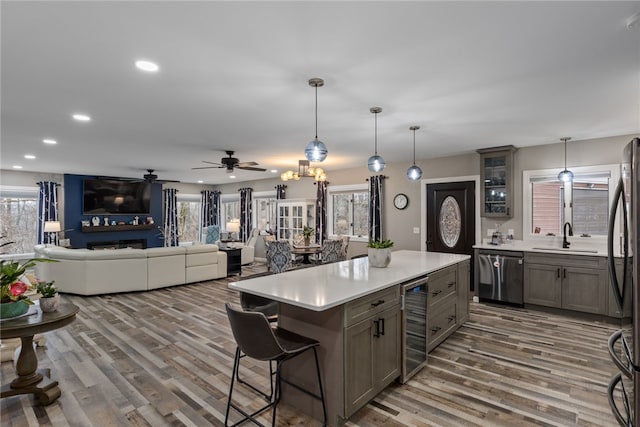 kitchen featuring a kitchen island, stainless steel dishwasher, wine cooler, and decorative light fixtures