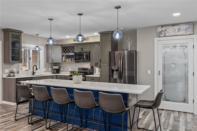 kitchen with sink, decorative light fixtures, stainless steel appliances, and a center island