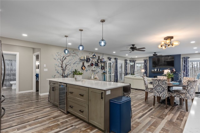 kitchen with hardwood / wood-style floors, wine cooler, a wealth of natural light, a kitchen island, and decorative light fixtures