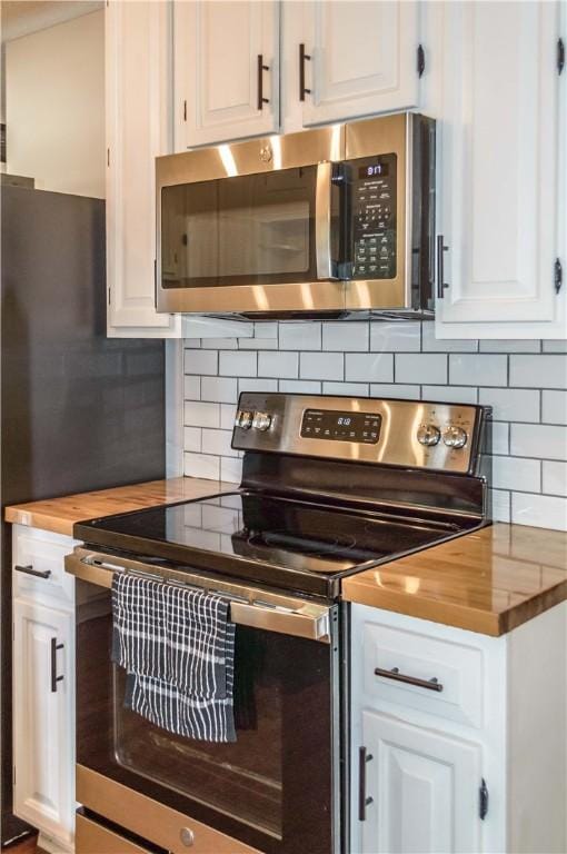 317 Hickory Ln, Mattoon, IL 61938 - kitchen with stainless steel appliances, butcher block countertops, white cabinets, and tasteful backsplash