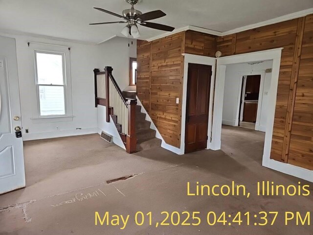 1102 3rd St, Lincoln, IL 62656 - unfurnished room featuring wooden walls, ceiling fan, stairs, carpet, and baseboards