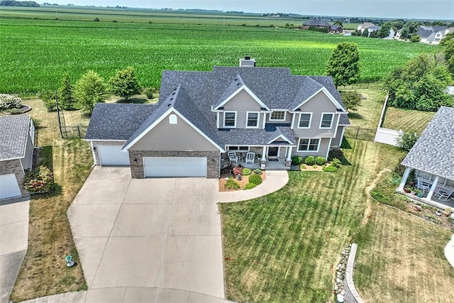 1008 Schroll Dr, Forsyth, IL 62535 - view of front of house featuring concrete driveway, a porch, a garage, a chimney, and a view of rural / pastoral area