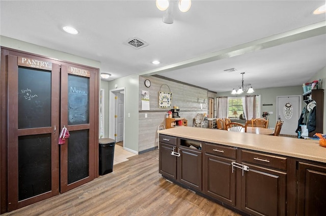 22417 N 1320th St, Marshall, IL 62441 - kitchen featuring dark brown cabinetry, light wood-type flooring, light countertops, a chandelier, and hanging light fixtures
