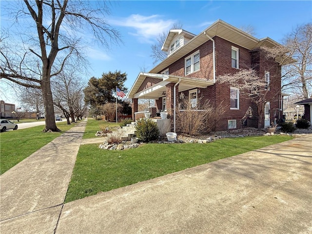 view of home's exterior featuring a porch, brick siding, and a yard