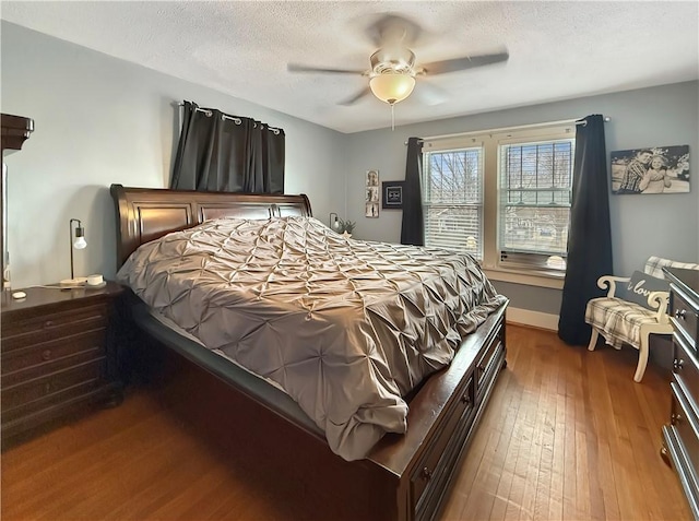 bedroom with ceiling fan, a textured ceiling, baseboards, and hardwood / wood-style flooring