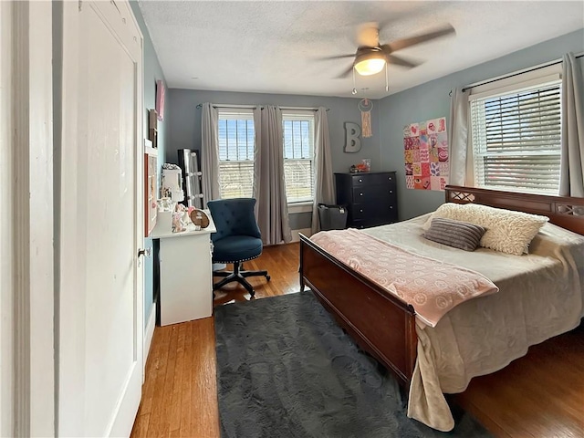 bedroom with ceiling fan, a textured ceiling, and wood finished floors