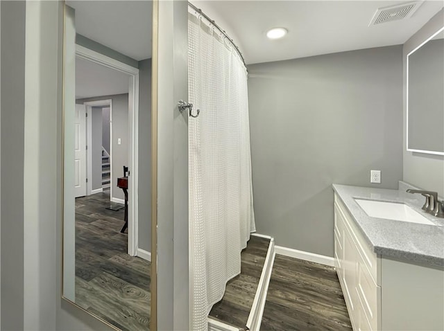 bathroom featuring baseboards, visible vents, a shower with shower curtain, wood finished floors, and vanity