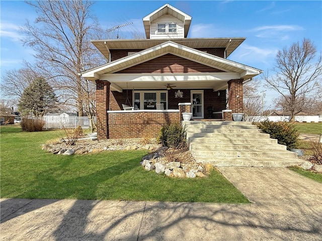 view of front of house with brick siding, a porch, a ceiling fan, fence, and a front lawn