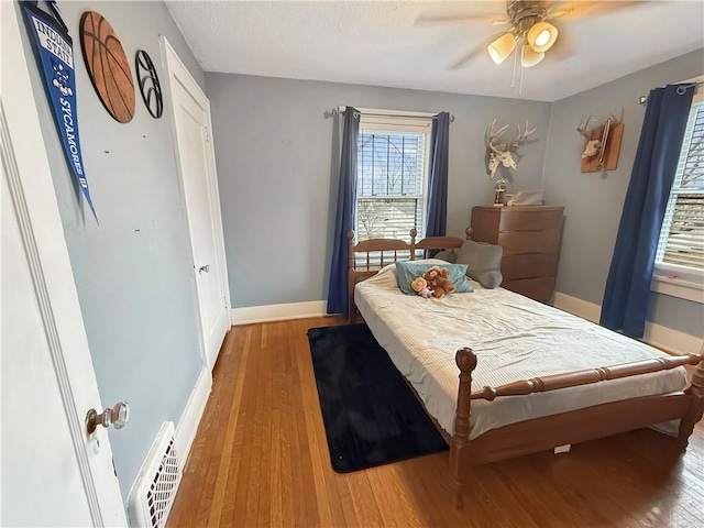 bedroom featuring light wood finished floors, baseboards, visible vents, and a ceiling fan