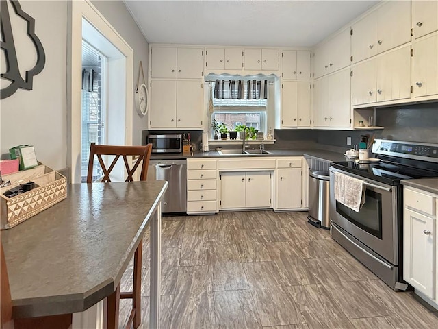 kitchen featuring appliances with stainless steel finishes, dark countertops, and a sink