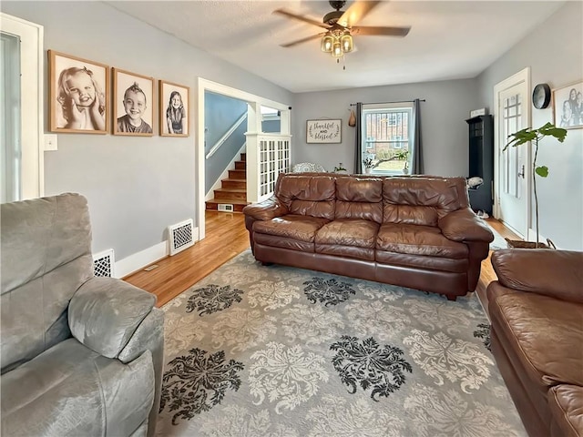 living room featuring a ceiling fan, baseboards, visible vents, and wood finished floors