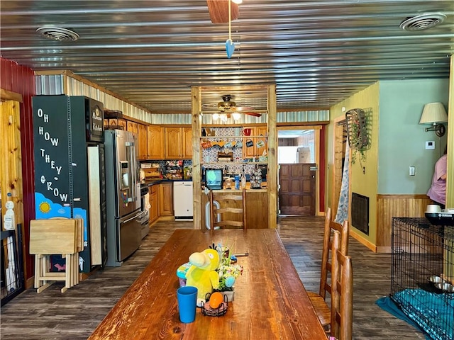 dining space with dark wood-type flooring, visible vents, a wainscoted wall, and ceiling fan