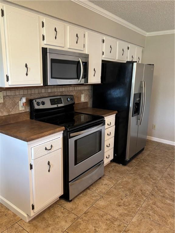 905 W Evergreen Ave, Effingham, IL 62401 - kitchen with appliances with stainless steel finishes, dark countertops, ornamental molding, tasteful backsplash, and white cabinetry