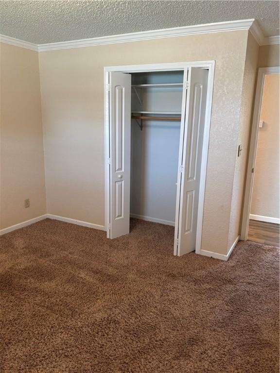 905 W Evergreen Ave, Effingham, IL 62401 - unfurnished bedroom featuring a textured ceiling, crown molding, carpet flooring, and a closet