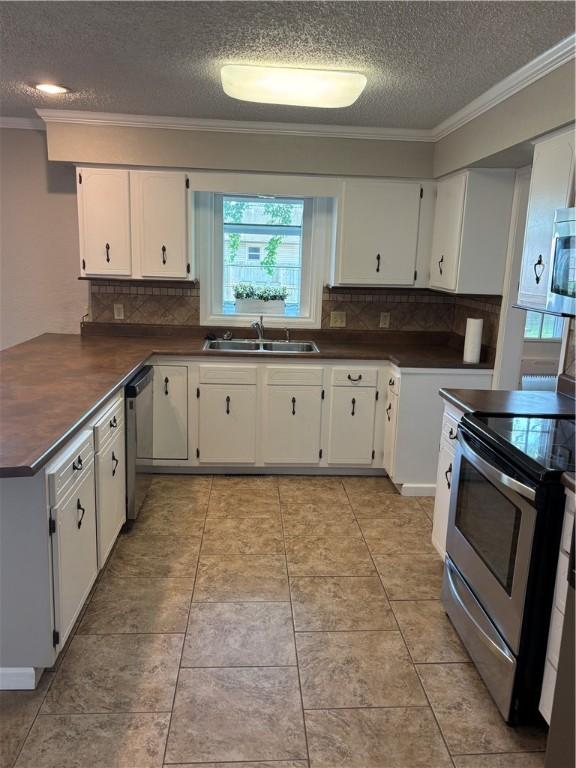 905 W Evergreen Ave, Effingham, IL 62401 - kitchen with appliances with stainless steel finishes, dark countertops, a textured ceiling, crown molding, and decorative backsplash