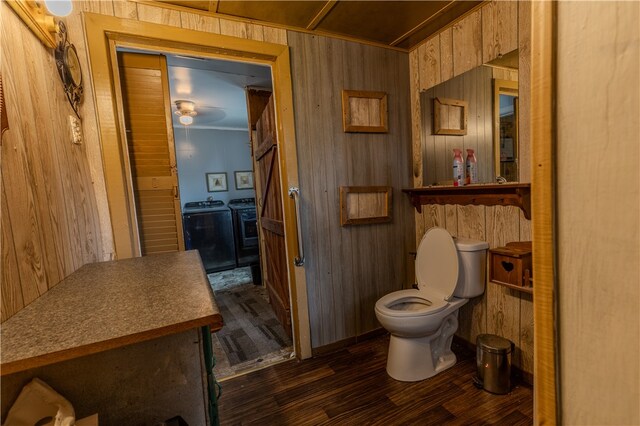 bathroom with washing machine and dryer, wooden walls, hardwood / wood-style floors, and toilet