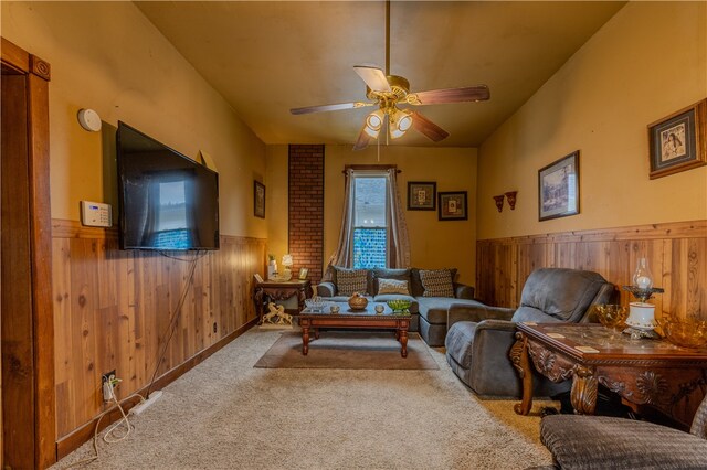 carpeted living room with ceiling fan and wood walls