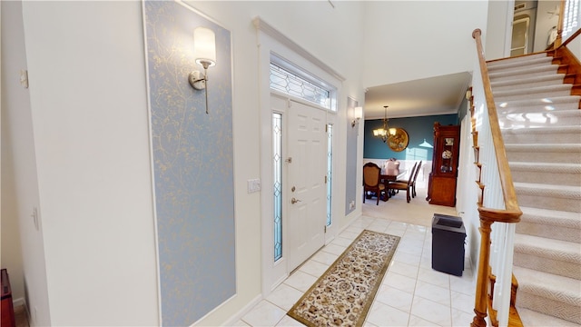 tiled foyer with a towering ceiling and a chandelier