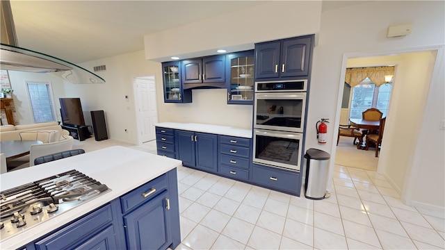 kitchen with light tile patterned floors, blue cabinetry, and stainless steel appliances