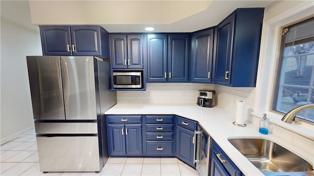 kitchen with tasteful backsplash, sink, blue cabinetry, and appliances with stainless steel finishes