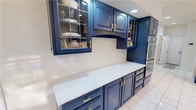 kitchen with blue cabinetry, light tile patterned floors, and double oven