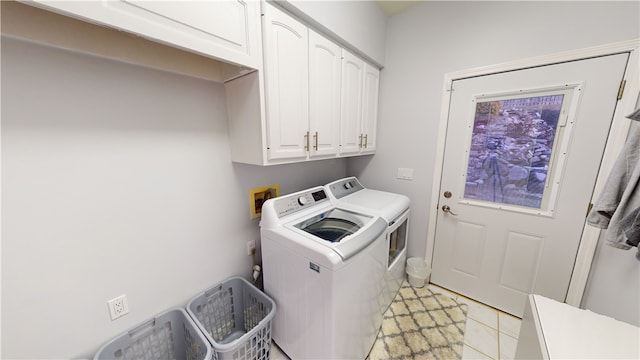 washroom with light tile patterned floors, washing machine and dryer, and cabinets