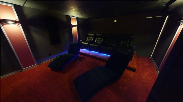 home theater featuring dark colored carpet and a paneled ceiling