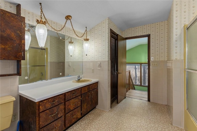 bathroom featuring wallpapered walls, tile walls, and a wainscoted wall