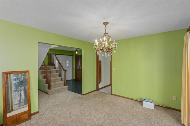 spare room featuring stairs, a notable chandelier, carpet flooring, and baseboards