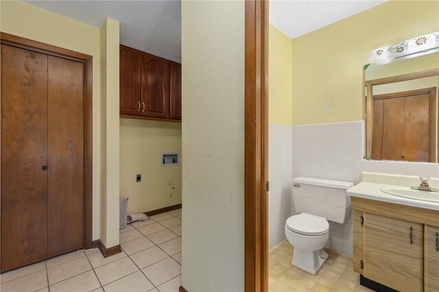 bathroom featuring tile patterned floors, toilet, tile walls, wainscoting, and vanity