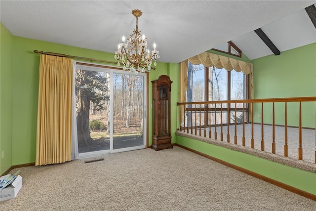 carpeted spare room with visible vents, a textured ceiling, baseboards, a chandelier, and vaulted ceiling