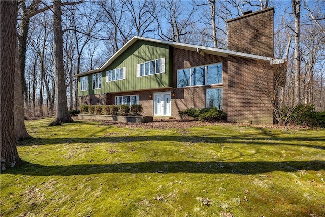 back of house featuring a lawn, brick siding, and a chimney