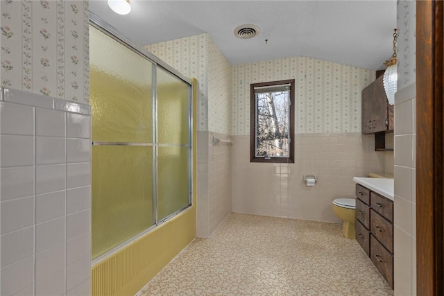 bathroom featuring wallpapered walls, tile walls, wainscoting, an enclosed shower, and vanity