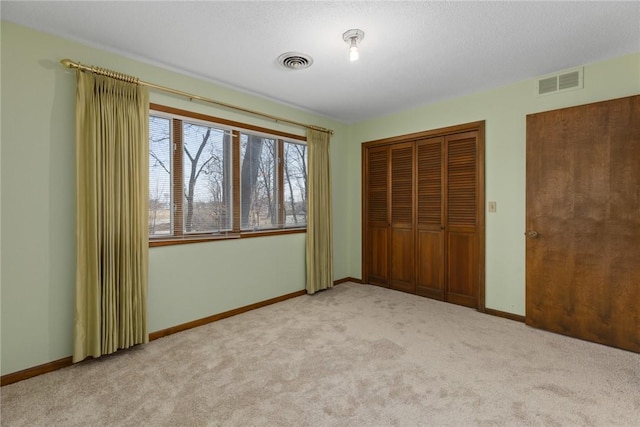 unfurnished bedroom featuring carpet flooring, baseboards, and visible vents