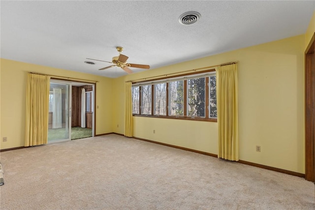 carpeted empty room with a ceiling fan, baseboards, visible vents, and a textured ceiling