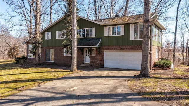 view of front facade featuring a front yard, an attached garage, brick siding, and driveway