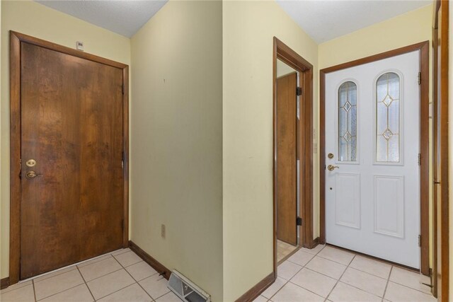 foyer entrance with light tile patterned floors, visible vents, and baseboards