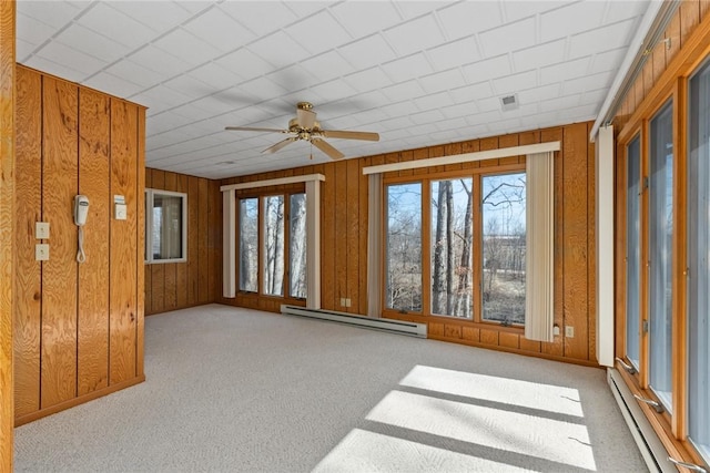 unfurnished room with carpet floors, wood walls, a baseboard heating unit, and a baseboard radiator