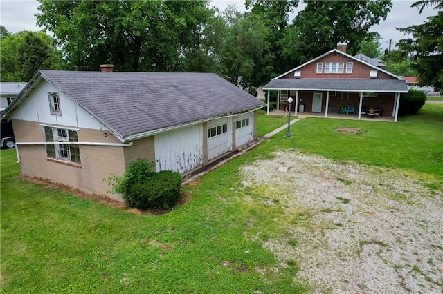 104 E N St, Ridgefarm, IL 61870 - rear view of house featuring a garage, a yard, roof with shingles, a chimney, and a patio area