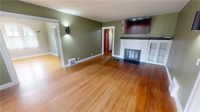 104 E N St, Ridgefarm, IL 61870 - unfurnished living room featuring a brick fireplace and wood finished floors
