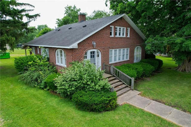 104 E N St, Ridgefarm, IL 61870 - tudor home with brick siding, a chimney, a front lawn, and a shingled roof
