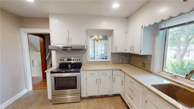 104 E N St, Ridgefarm, IL 61870 - kitchen featuring under cabinet range hood, stainless steel electric range oven, backsplash, light wood-style flooring, and white cabinetry
