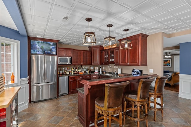 kitchen with a breakfast bar area, kitchen peninsula, hanging light fixtures, and appliances with stainless steel finishes