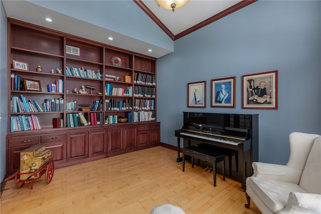 sitting room with light wood-type flooring, ornamental molding, and high vaulted ceiling