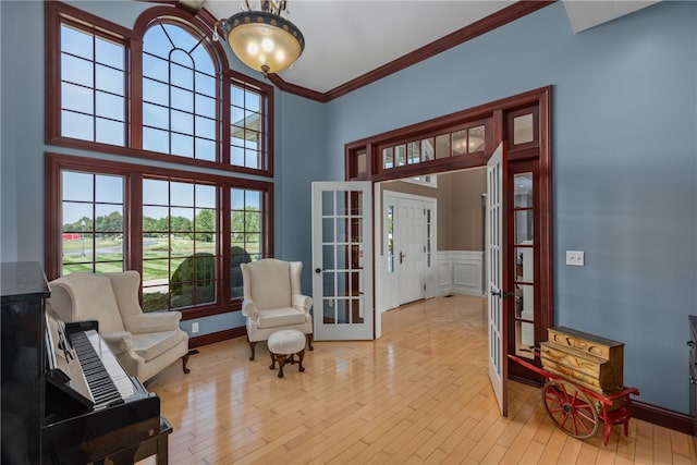 living area featuring plenty of natural light, light hardwood / wood-style floors, crown molding, and french doors