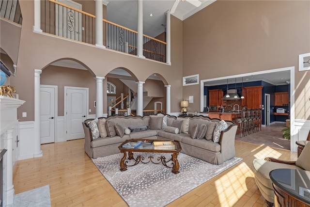 living room with ornamental molding, a high ceiling, and light wood-type flooring