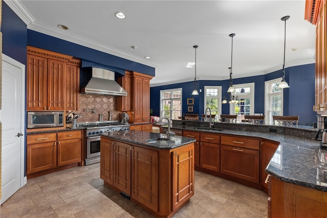 kitchen featuring hanging light fixtures, sink, stainless steel appliances, and wall chimney range hood