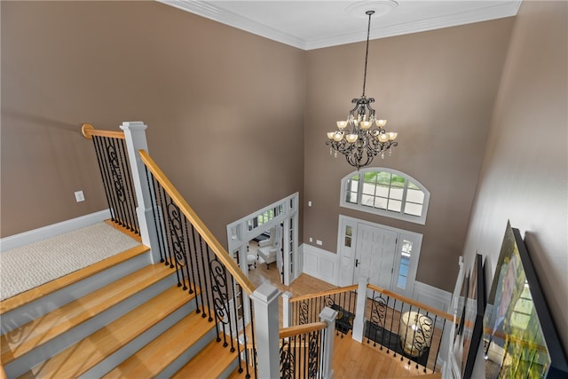 foyer featuring a high ceiling, ornamental molding, a notable chandelier, and hardwood / wood-style floors