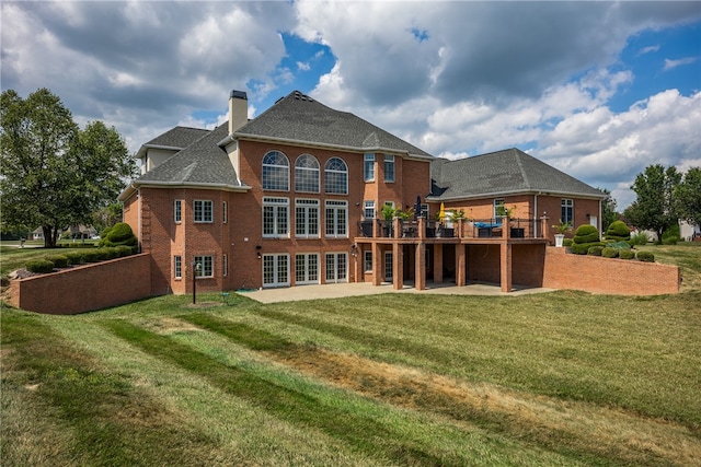 rear view of property featuring a yard, a patio, and a deck